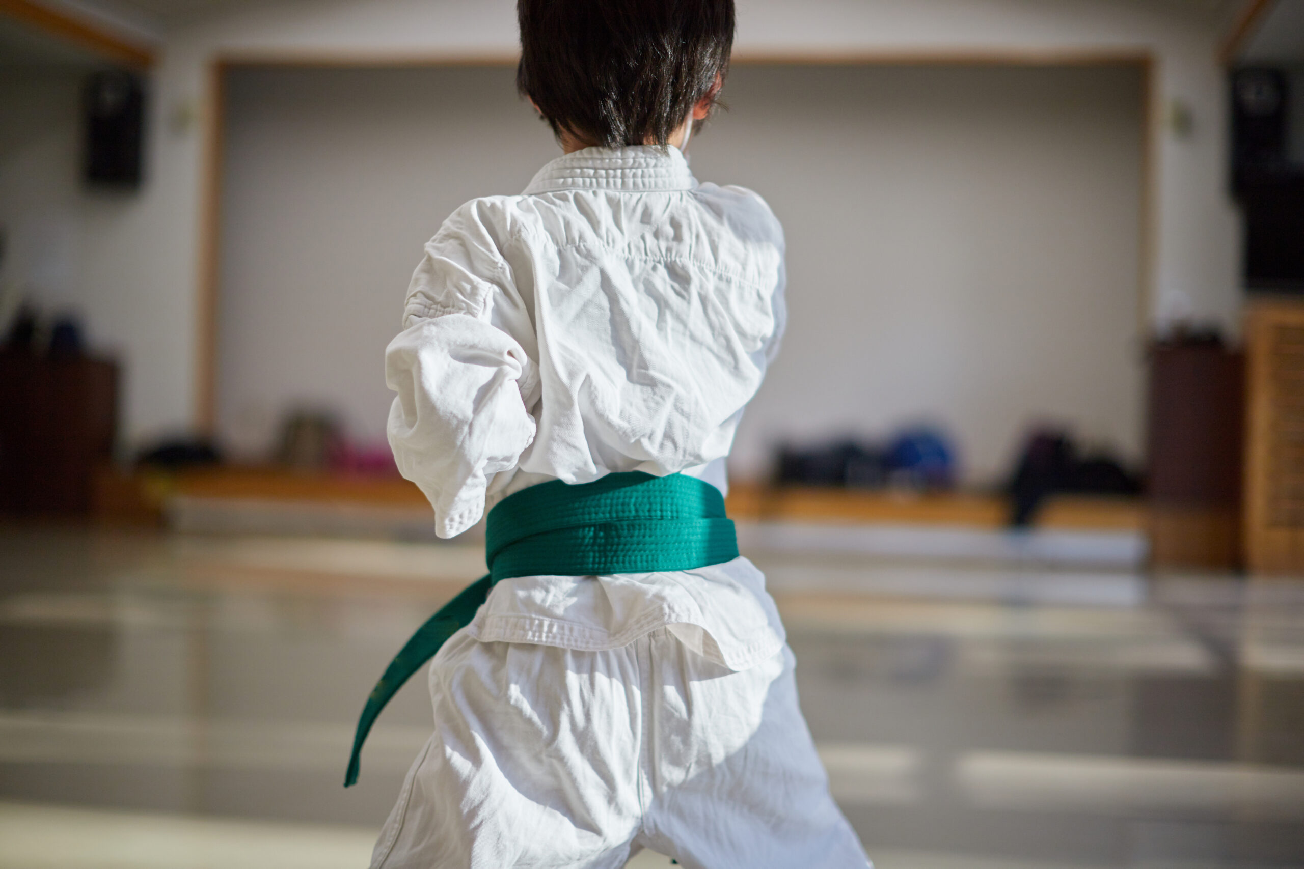 道場で帯を締めた子どもが一人で稽古に向き合う後ろ姿