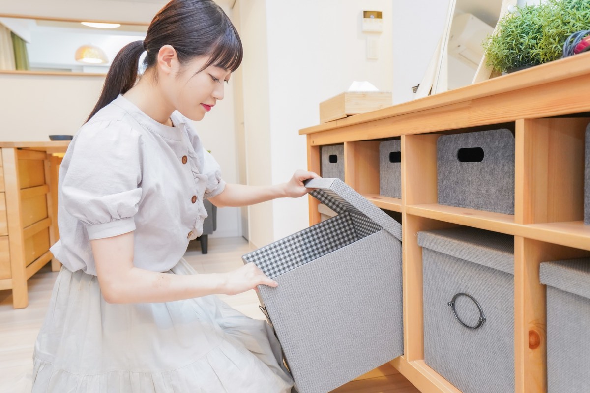 棚の中身を片付ける女性。手放す順番を決めるイメージ