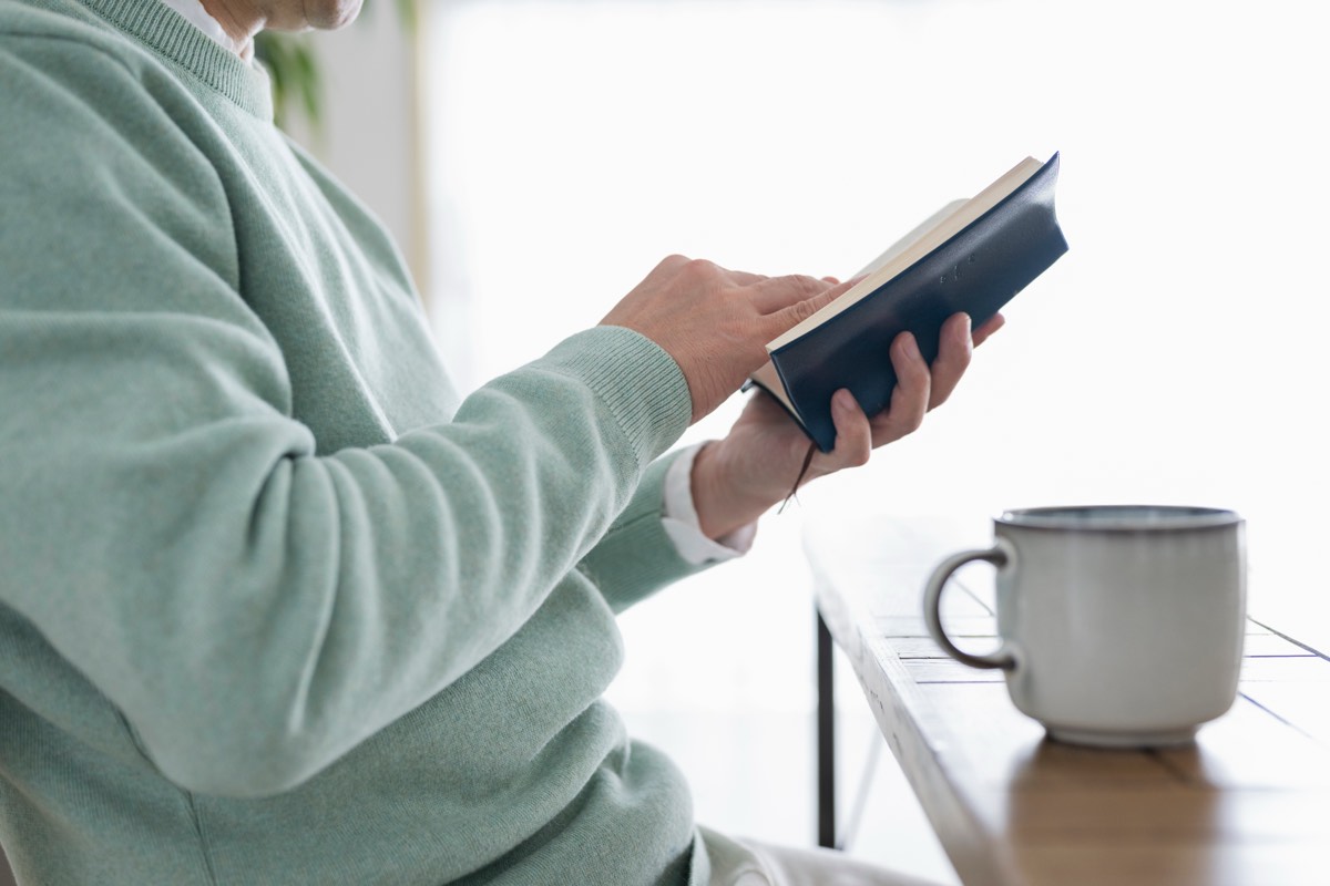 【要約】賢者の書|喜多川泰が9人の賢者に託した教えと、54歳の再読メモ 賢者の書の要約を書くために、休日に読書をしている50代男性のイメージ