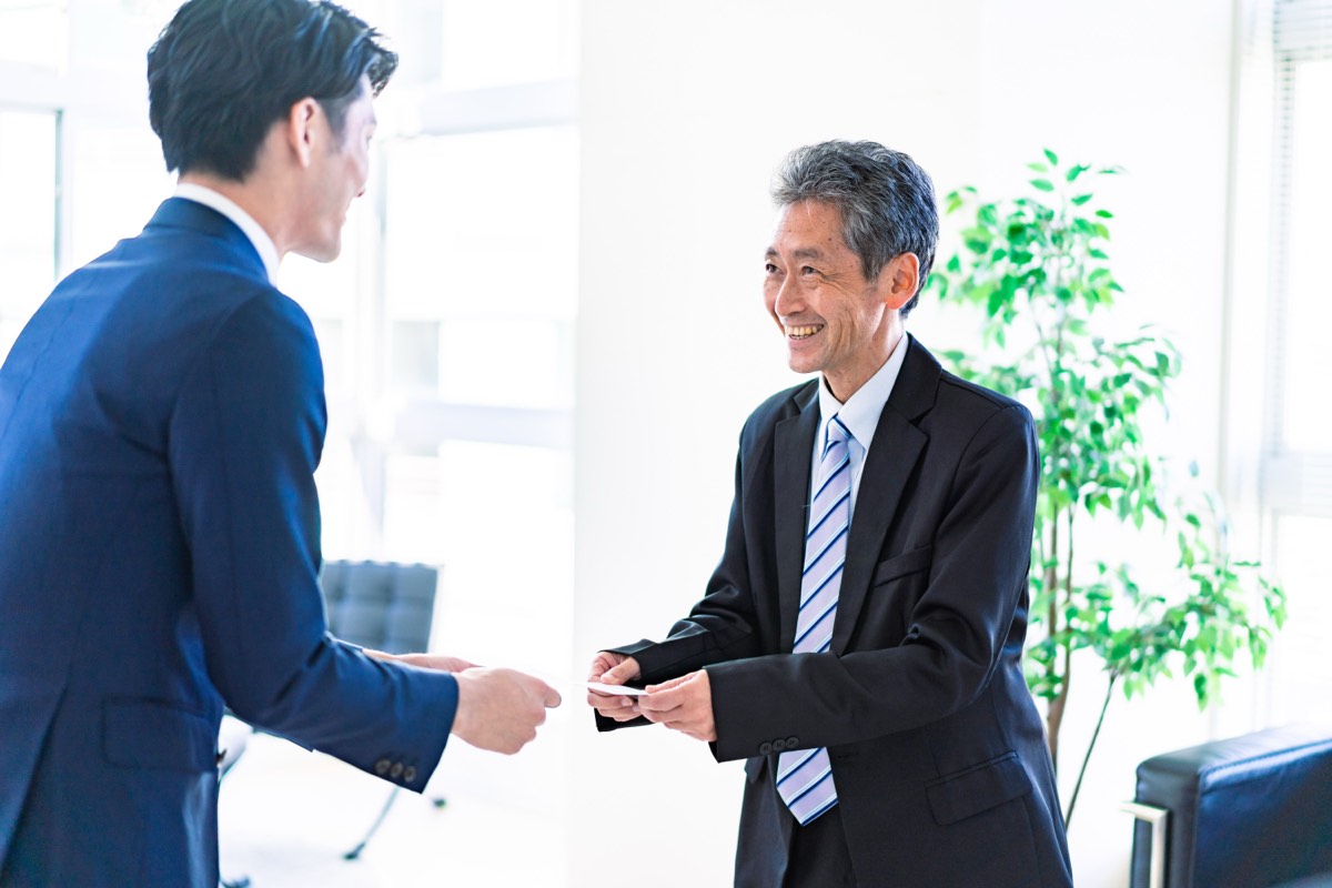 運転者の要約｜上機嫌でいることが出会いを生む。名刺を交換するビジネスマン
