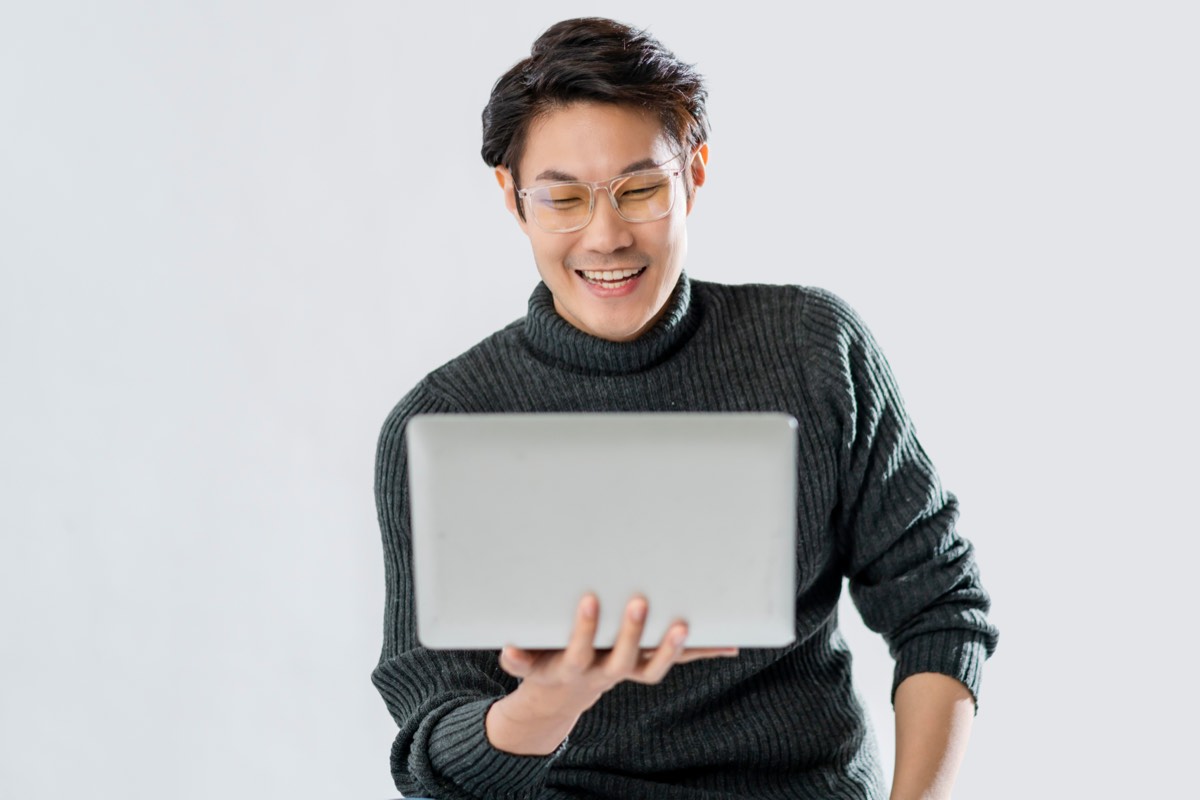 眼鏡をかけた中年の男性がノートパソコンの前で穏やかに笑う様子。あなた次第でこの世界は素晴らしい場所になるの要約を50代がどう受け取るかを表す場面
