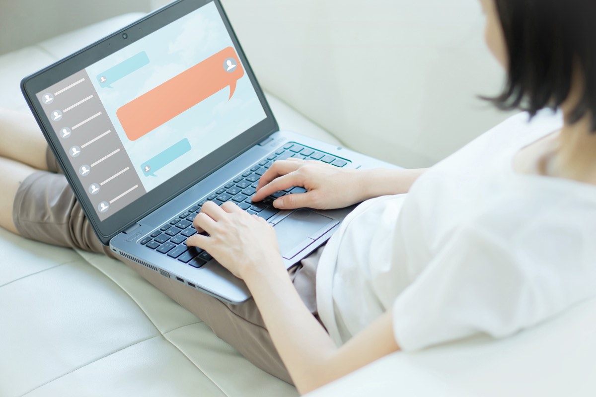 ノートパソコンでサポートのチャット画面を開く女性。Adobeの解約について公式窓口に問い合わせる場面