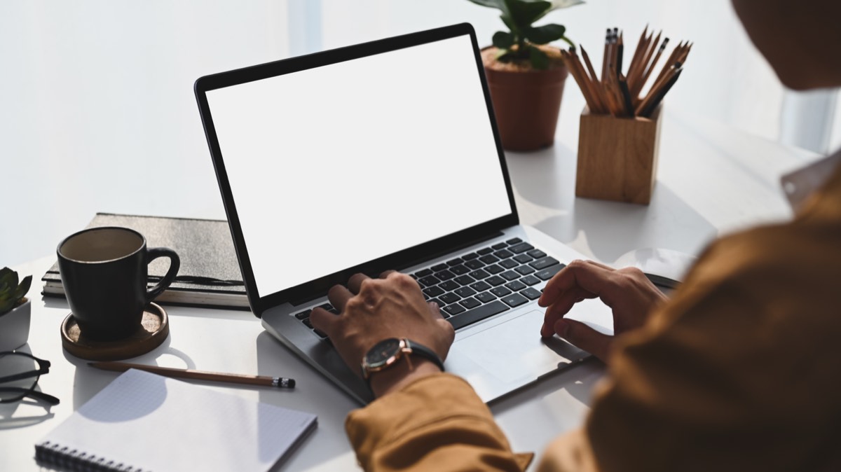 明るい部屋でノートパソコンに向かう男性の後ろ姿。Adobeの解約料がいくらかを画面で確認する場面