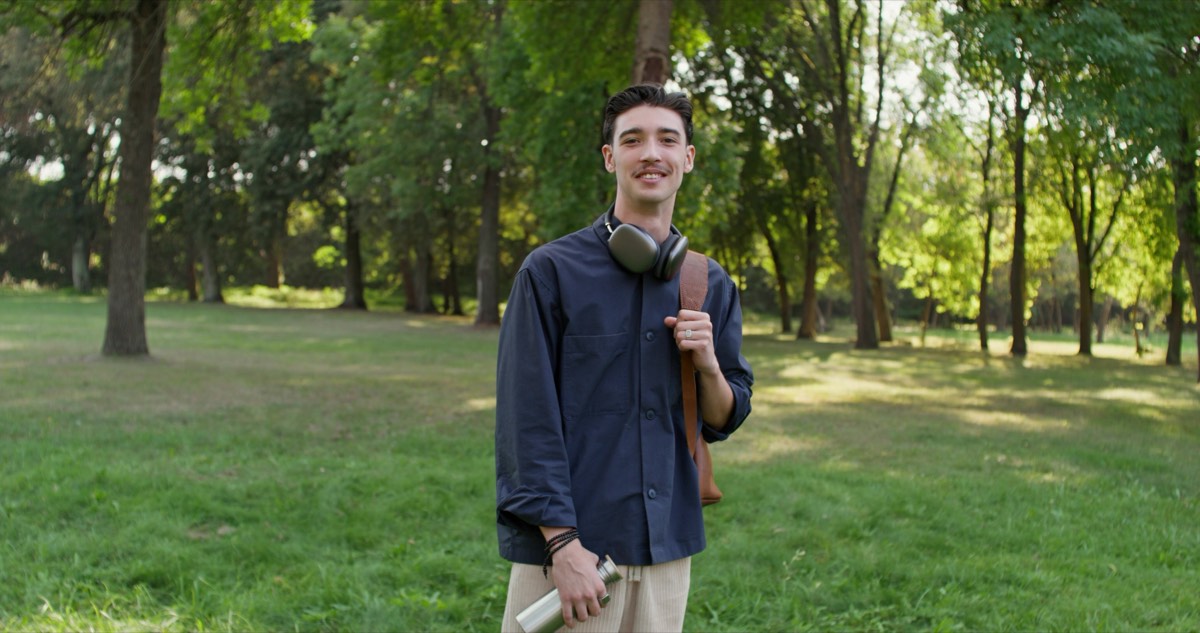 公園でヘッドホンを首にかけて立つ男性。何が問題なんですかの要約で選んだ1本をAudibleで聴く場面