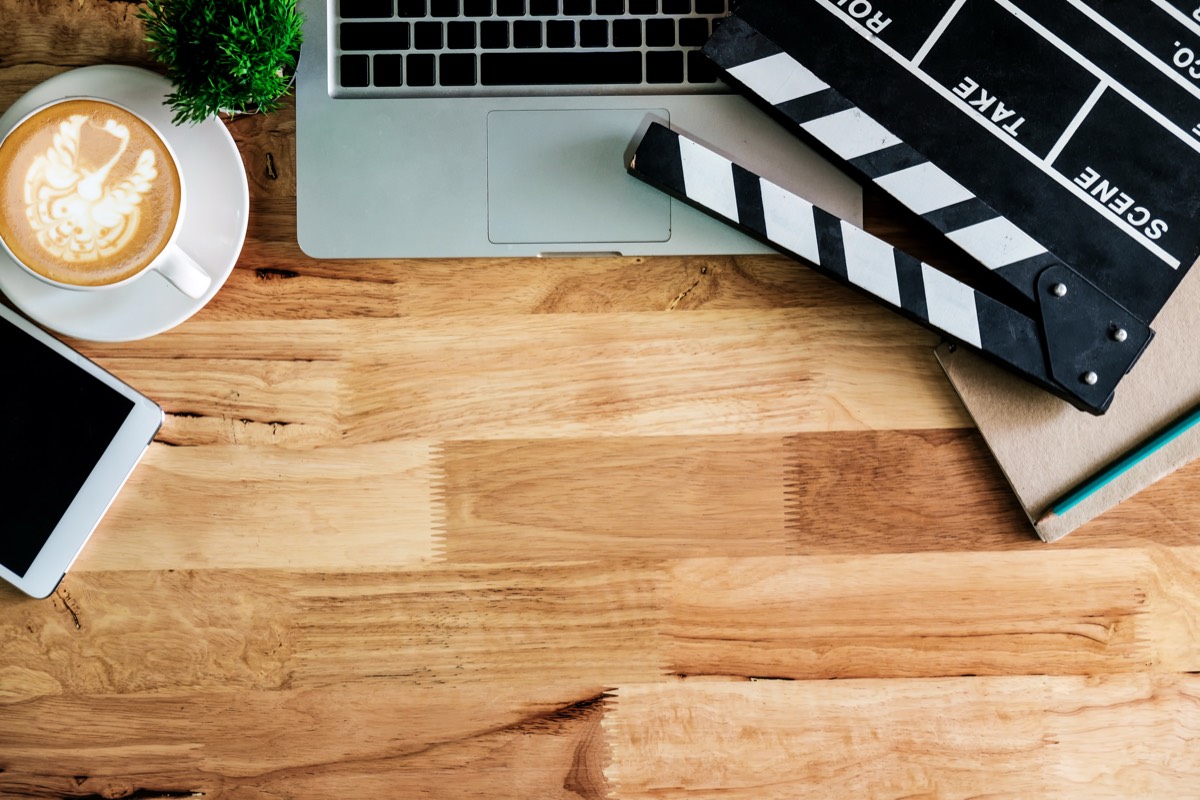 ノートパソコンと映画のカチンコとコーヒーを上から見た机