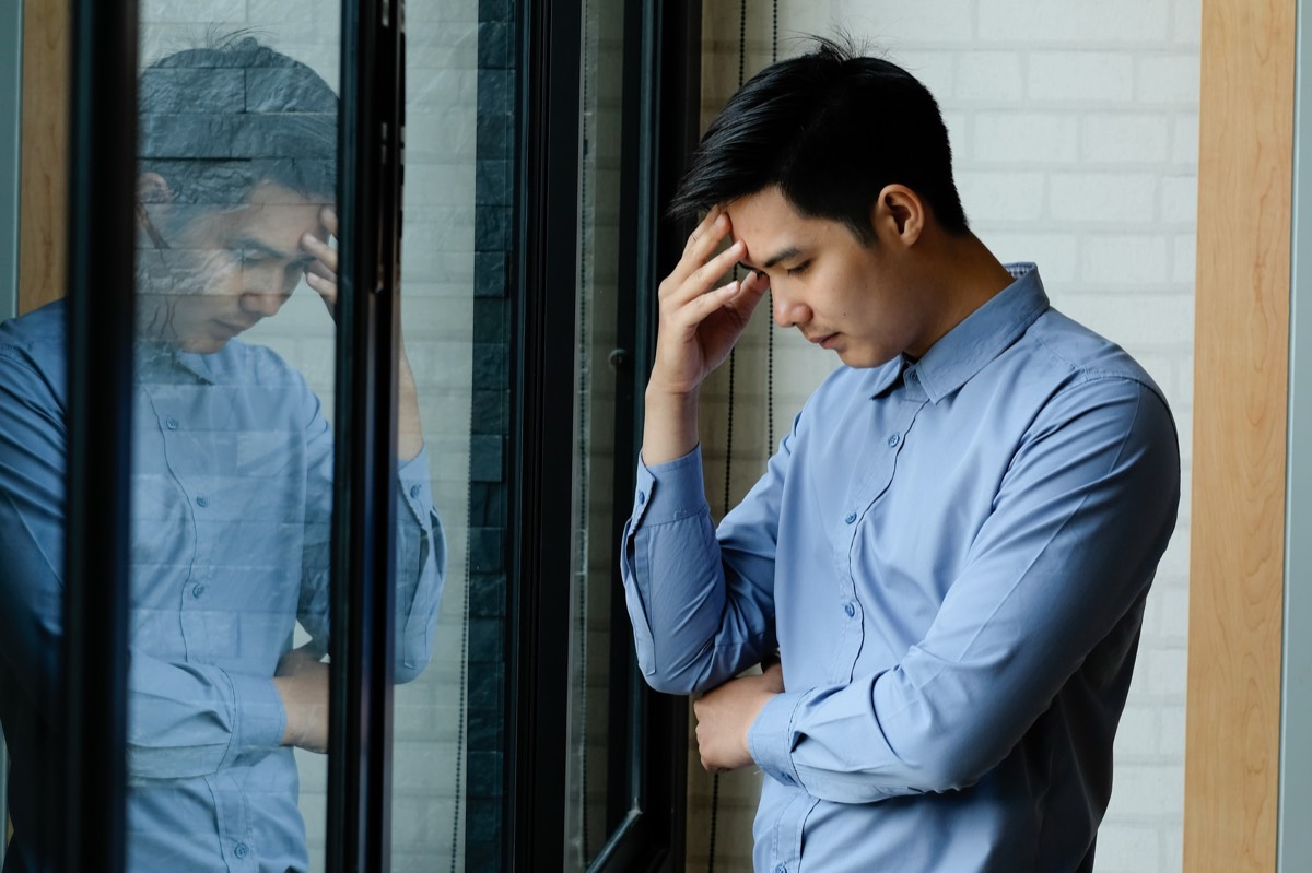 考えすぎて疲れる50代の男性が額に手を当てる様子