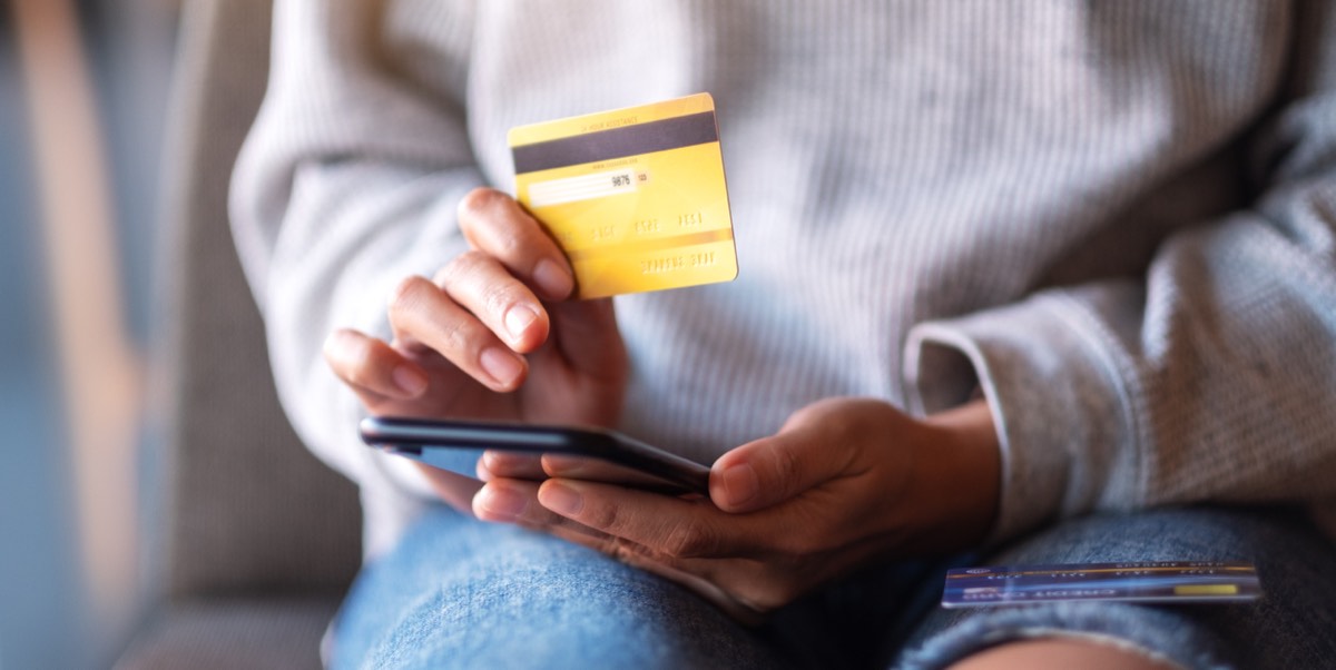 スマホとクレジットカードを手にネットで支払う女性の手元