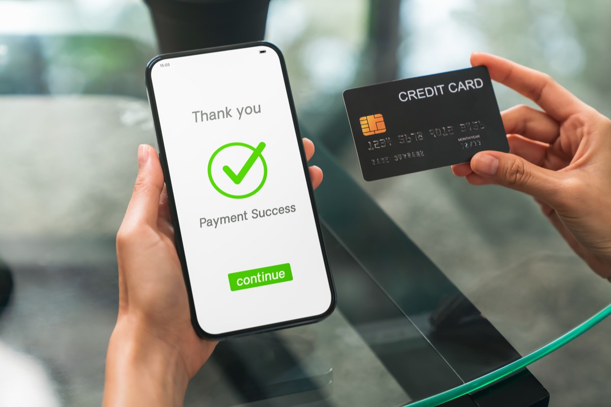 スマホの画面に支払い完了の表示とクレジットカードを持つ手