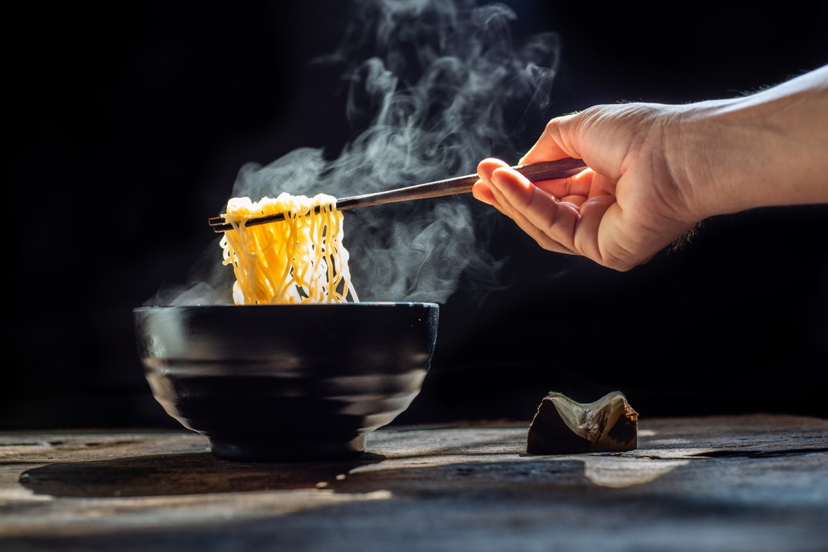 湯気の立つラーメンを箸で持ち上げる手元。お金が減るのが怖いと感じるランチの会計前