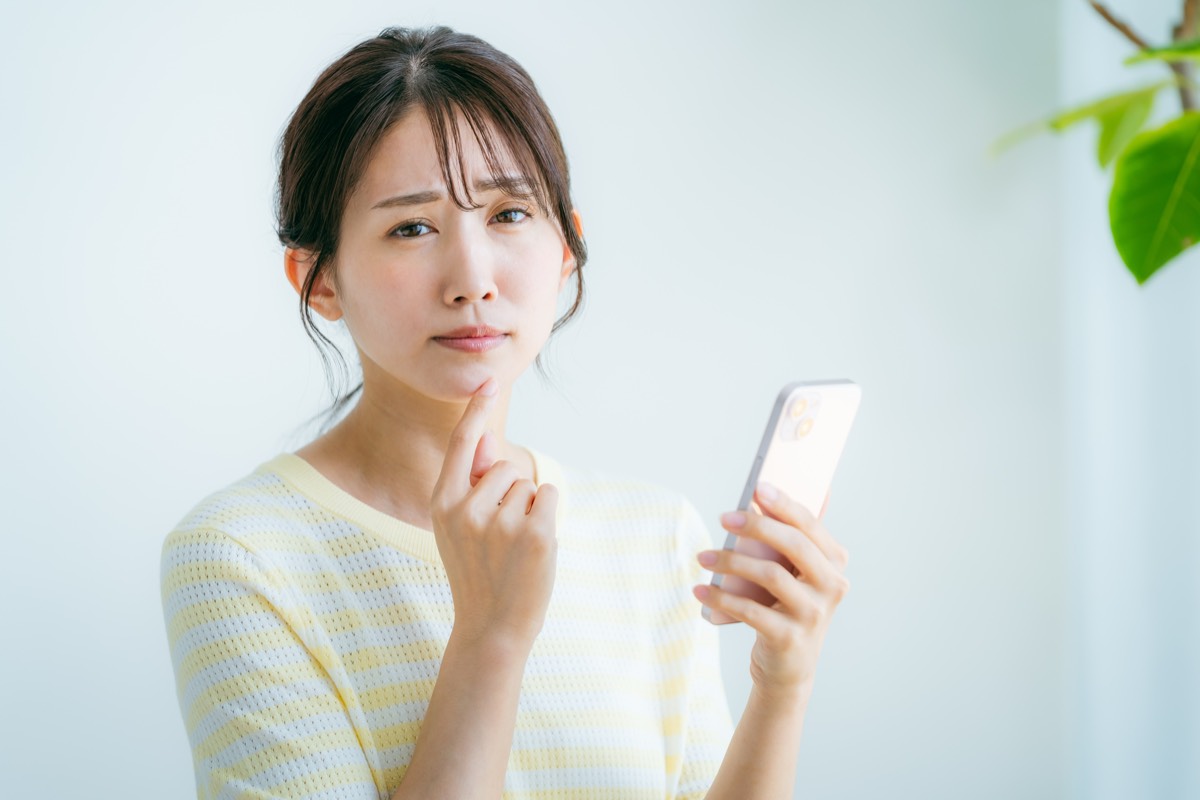 部屋でスマホを操作する女性