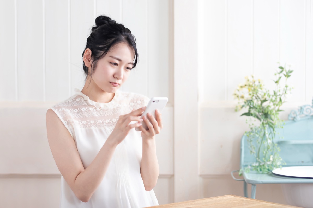 スマホを見て困った顔をする女性