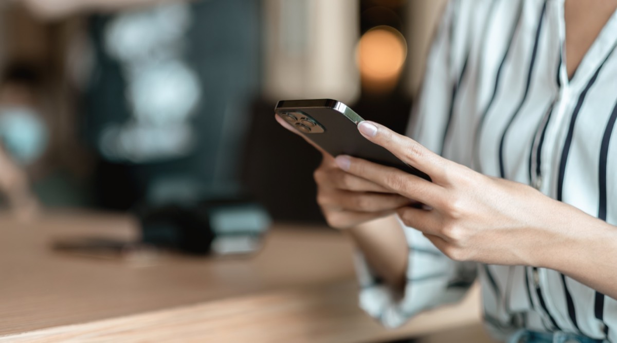 年賀状の無料テンプレートを探すために、カフェでスマホを操作する手元