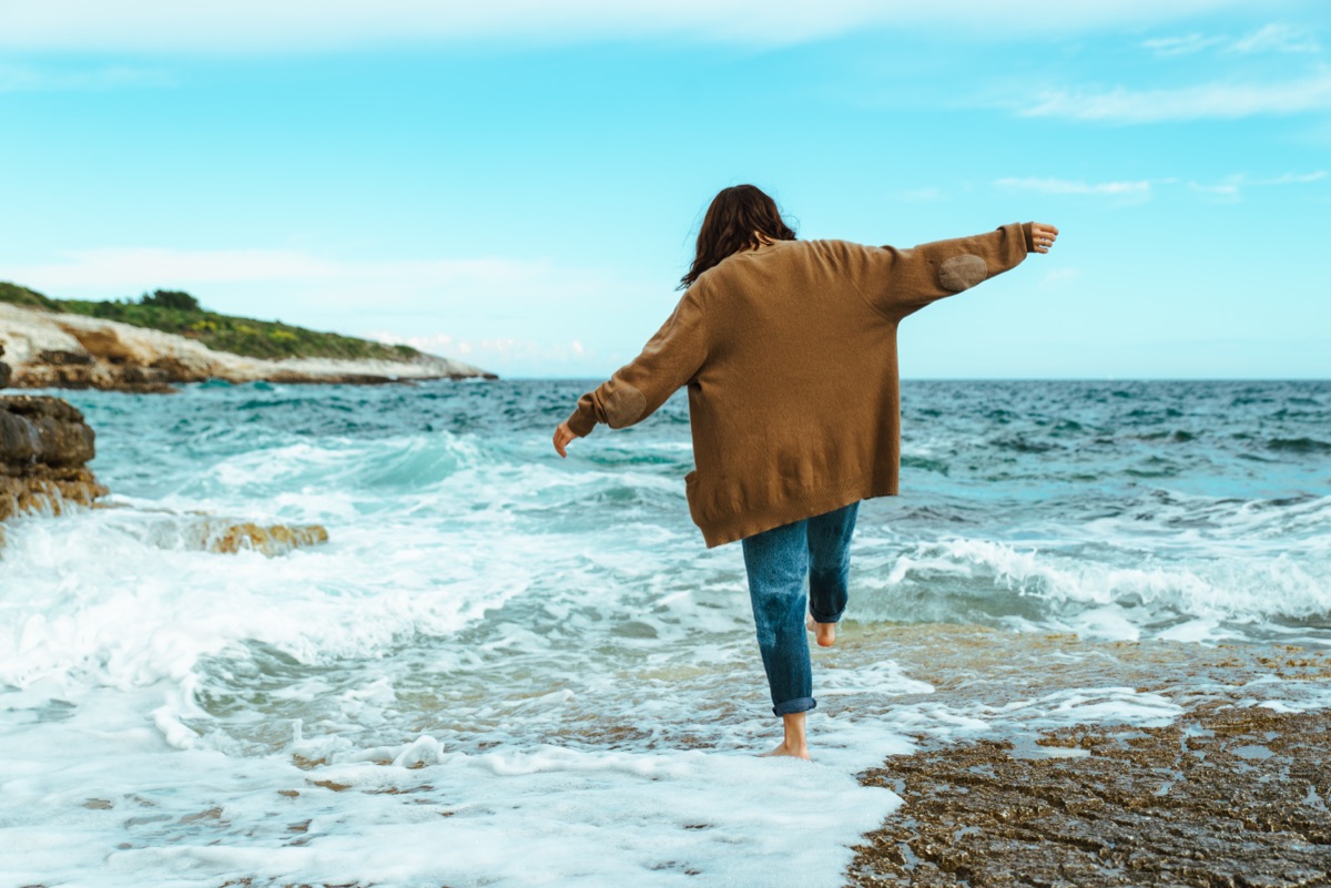 Photoshopの削除ツールで消す前の写真。海辺の岩場を歩く人