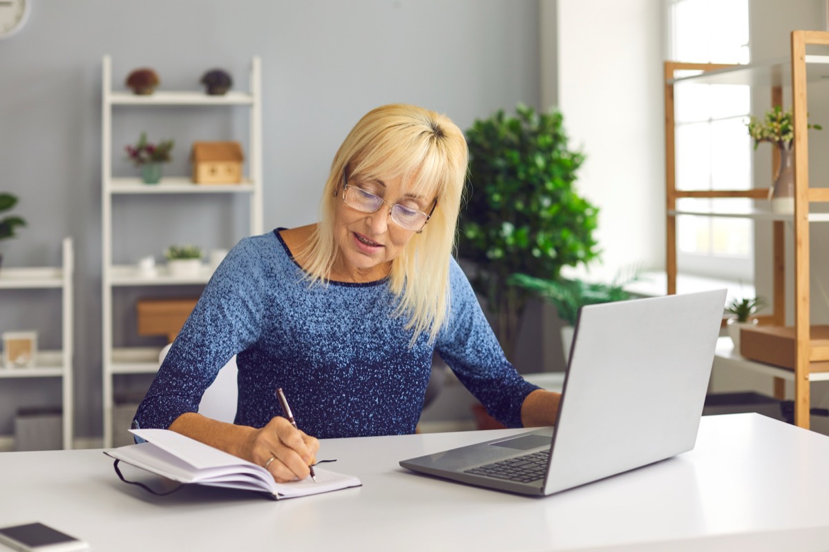 オンライン講座を見ながらノートを取るシニア女性。50代からのAIとマーケティングの学び