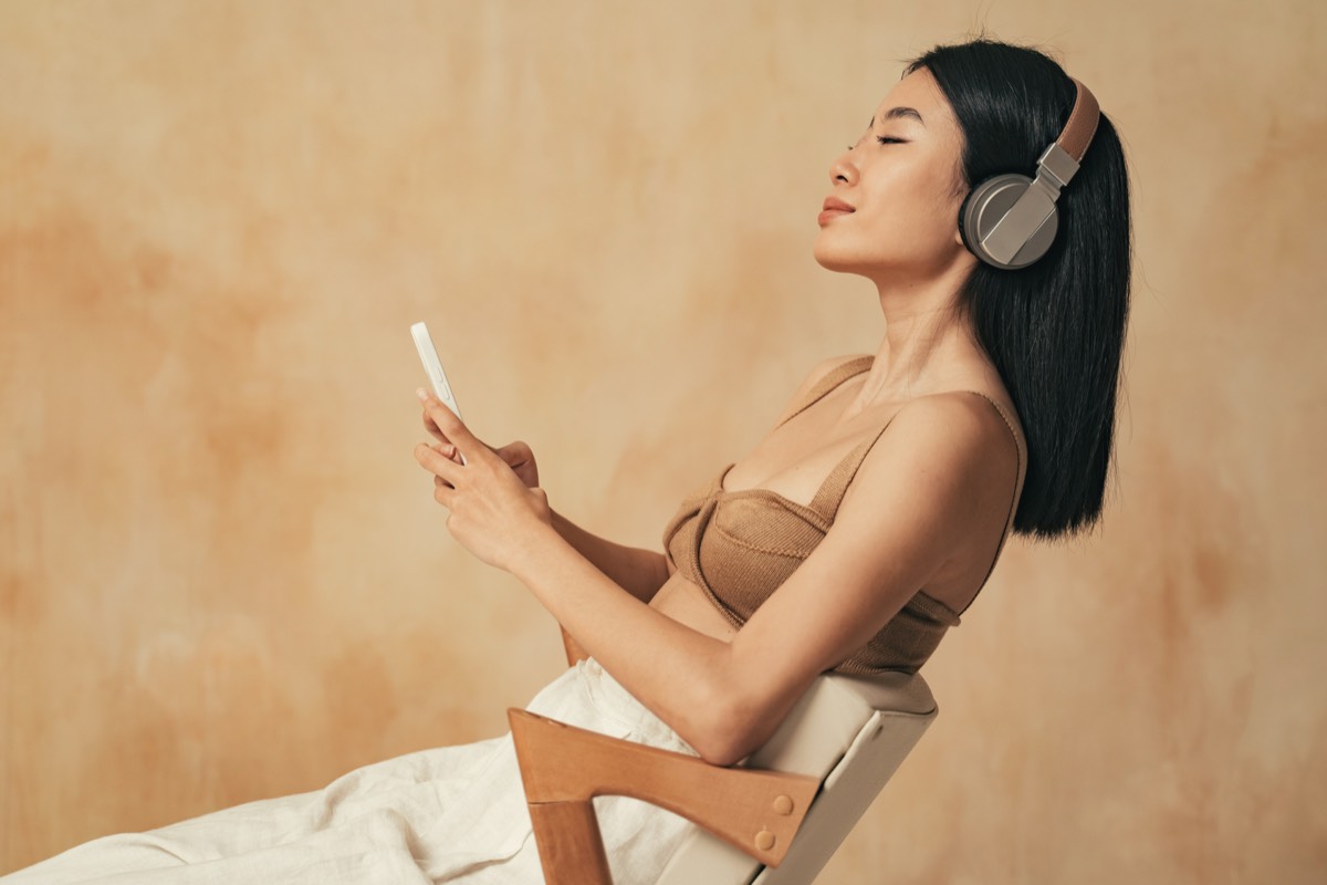 ヘッドホンで好きな音楽を聴いてくつろぐ女性